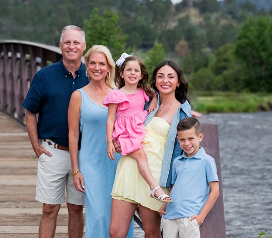 Brad Bailey and his family smile in front of a footbridge